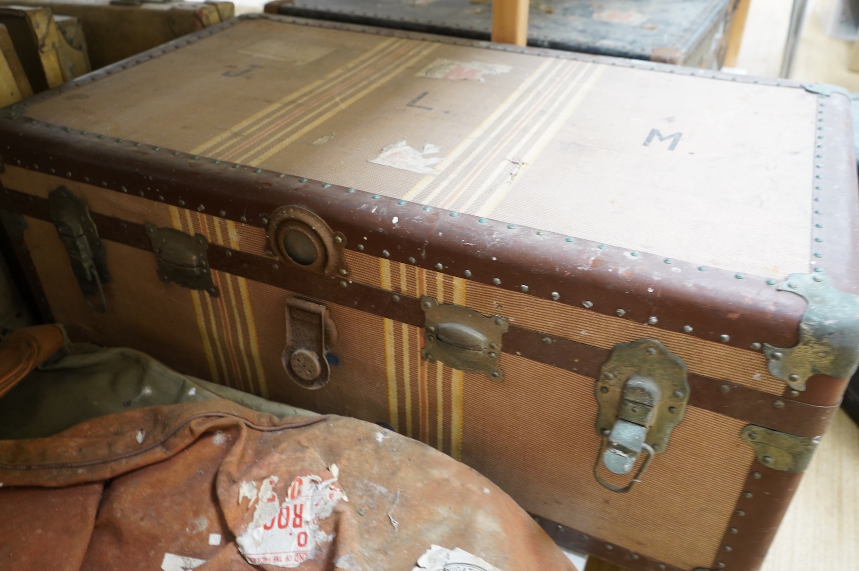 A collection of vintage luggage comprising four early 20th century bound travelling trunks and three kit bags